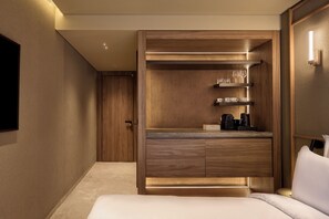 A modern hotel room with a built-in wooden wardrobe, a flat-screen TV mounted on the wall, and a bed with white bedding. - Nur Coreon Signature Hotel (Athens)