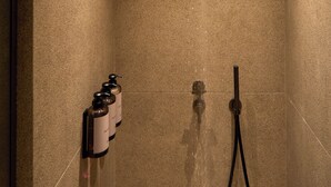 A modern shower with a rain showerhead, a handheld showerhead, and a bottle of shampoo. - Nur Coreon Signature Hotel (Athens)