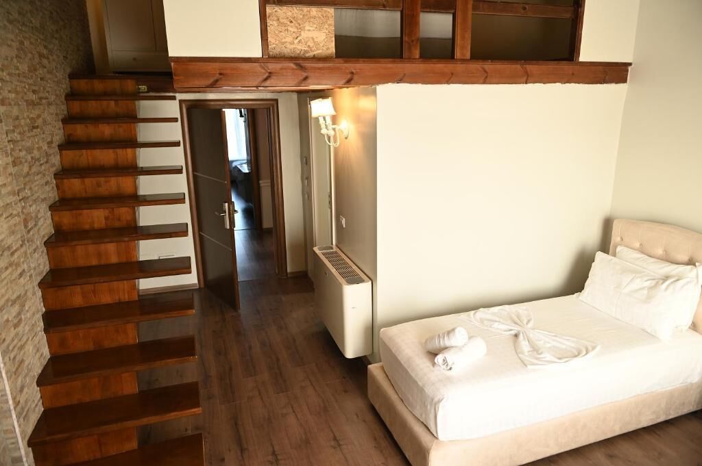 Ein Schlafzimmer mit einer Holztreppe, einem Bett mit weißen Leinen und einem Nachttisch mit Lampe.