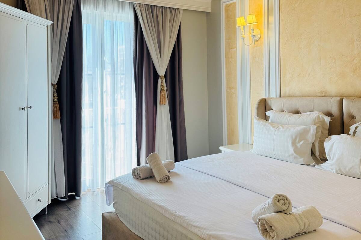 A hotel room with a large bed, a wardrobe, and a nightstand.
