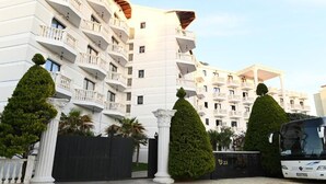 A multi-story hotel with balconies, a covered entrance, and a black car parked in front. - Hotel Onufri (Golem)