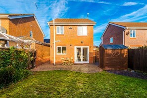 A two-story brick house with a patio, a wooden shed, and a well-maintained lawn. - Peaceful 3 Bedroom Detached Home with ample parking, 7 mins to Chester (Saltney)