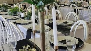 A dining area with white chairs, a table set with plates, glasses, and a centerpiece of white flowers. - Phola la bed and Breakfast (eMthonjaneni)