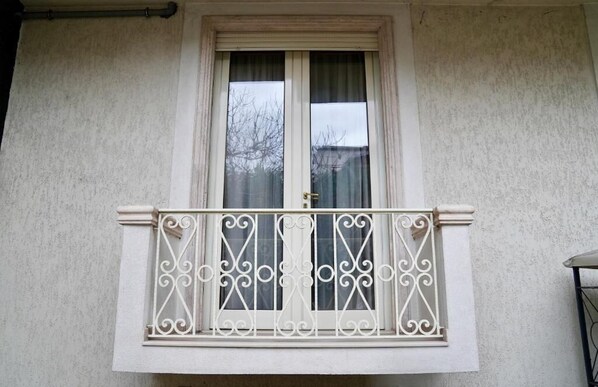 Una ventana con balaustrada blanca y una puerta cerrada.