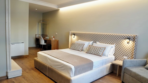 A modern hotel room with a large bed, a bedside table, a chair, and a mirror. - Hortus Hotel Tirana (Tirana)