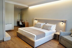 Una habitación de hotel moderna con una cama grande, una mesita de noche, una silla y un espejo.