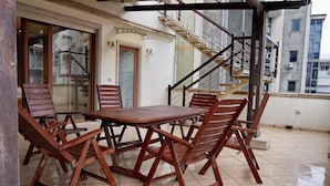 A patio with a wooden table and chairs, a glass door, and a staircase leading to an upper floor. - Hortus Hotel Tirana (Tirana)