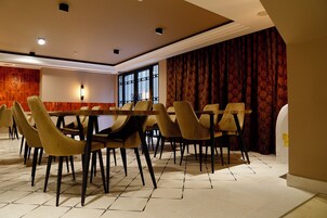 Un comedor con una mesa larga y varias sillas, un muro con diseño y un ventanal grande.