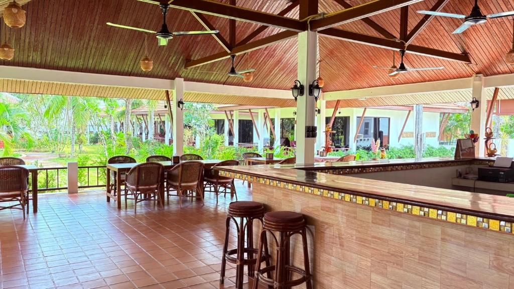 An outdoor covered dining area with wooden flooring, bar stools, and ceiling fans.