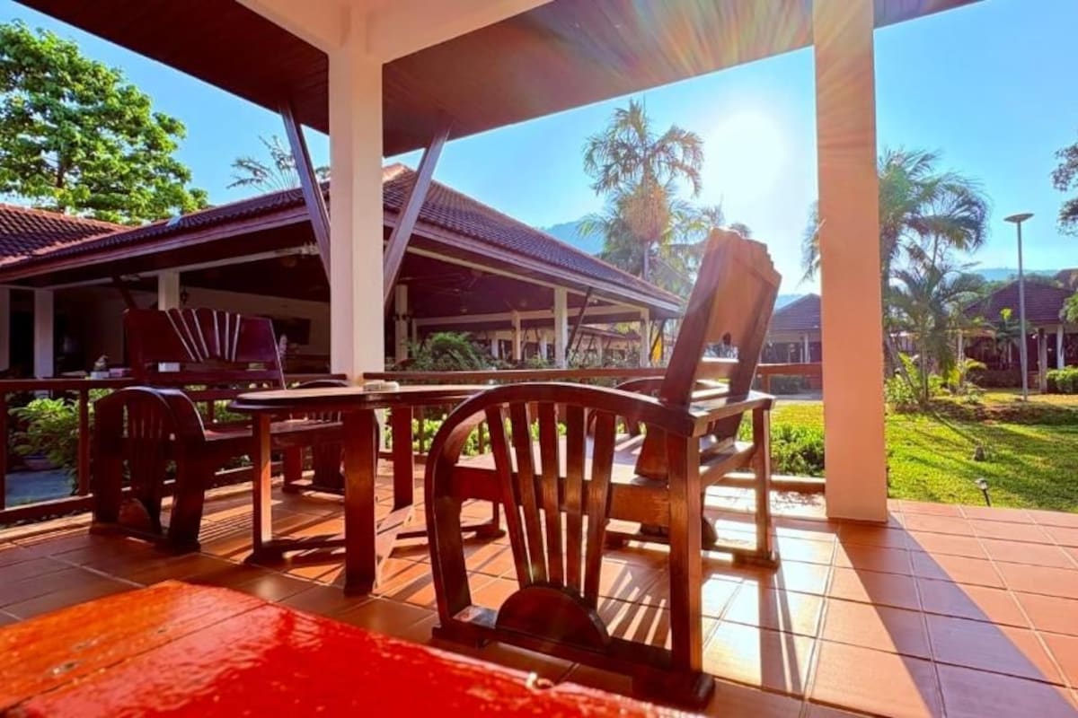 An outdoor seating area with wooden furniture and a covered structure.