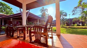 An outdoor seating area with wooden furniture and a covered structure. - Kamala Garden Bungalows (Kamala)
