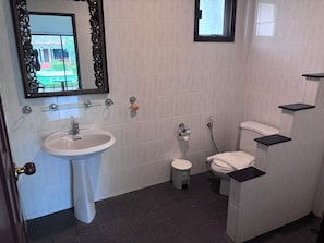 A bathroom with a pedestal sink, toilet, and a shower area. - Kamala Garden Bungalows (Kamala)