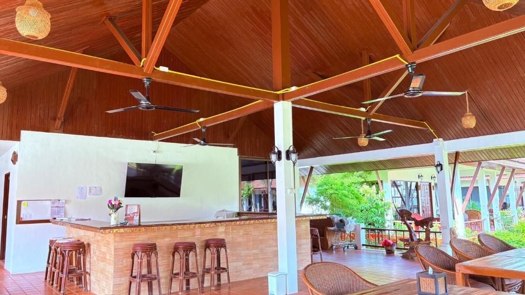 A covered outdoor area with a bar, seating, and ceiling fans.