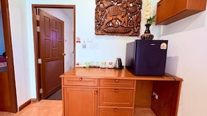 Un escritorio de madera con un refrigerador oscuro, un panel decorativo en la pared y una puerta con contraventana.