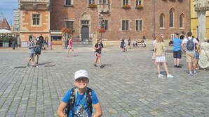 A historic building with intricate architecture, a large clock, and a cobblestone plaza. - La Casa de Magdasa 3 (Warsaw)
