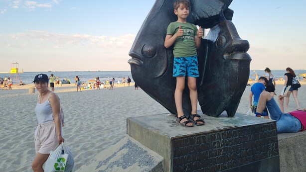A beach scene with a large sculpture of a fish head, a lifeguard tower, and people enjoying the beach. - La Casa de Magdasa 3 (Warsaw)
