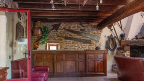 A rustic interior with a stone wall, wooden furniture, and a fireplace.