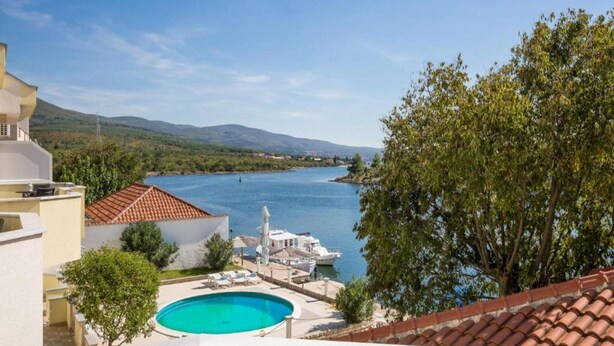 Uma área de piscina com vista para um lago e montanhas ao fundo.