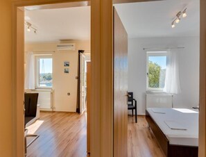 Ein Zimmer mit Bett, Stuhl, Schreibtisch und einem Fenster mit Meerblick.