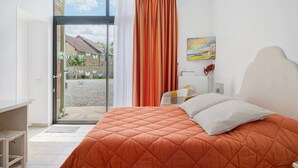 Un dormitorio con cama, escritorio y vista al exterior.