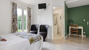 A bedroom with a bed, two chairs, a TV, a desk, and a green wall. - Bed and Breakfast 'Les Malvaux - Chambre Verte' with Shared Pool, Shared Terrace and Wi-Fi (Huriel)
