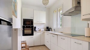 A kitchen with white cabinets, a microwave, an oven, and a window. - Bed and Breakfast 'Les Malvaux - Chambre Verte' with Shared Pool, Shared Terrace and Wi-Fi (Huriel)