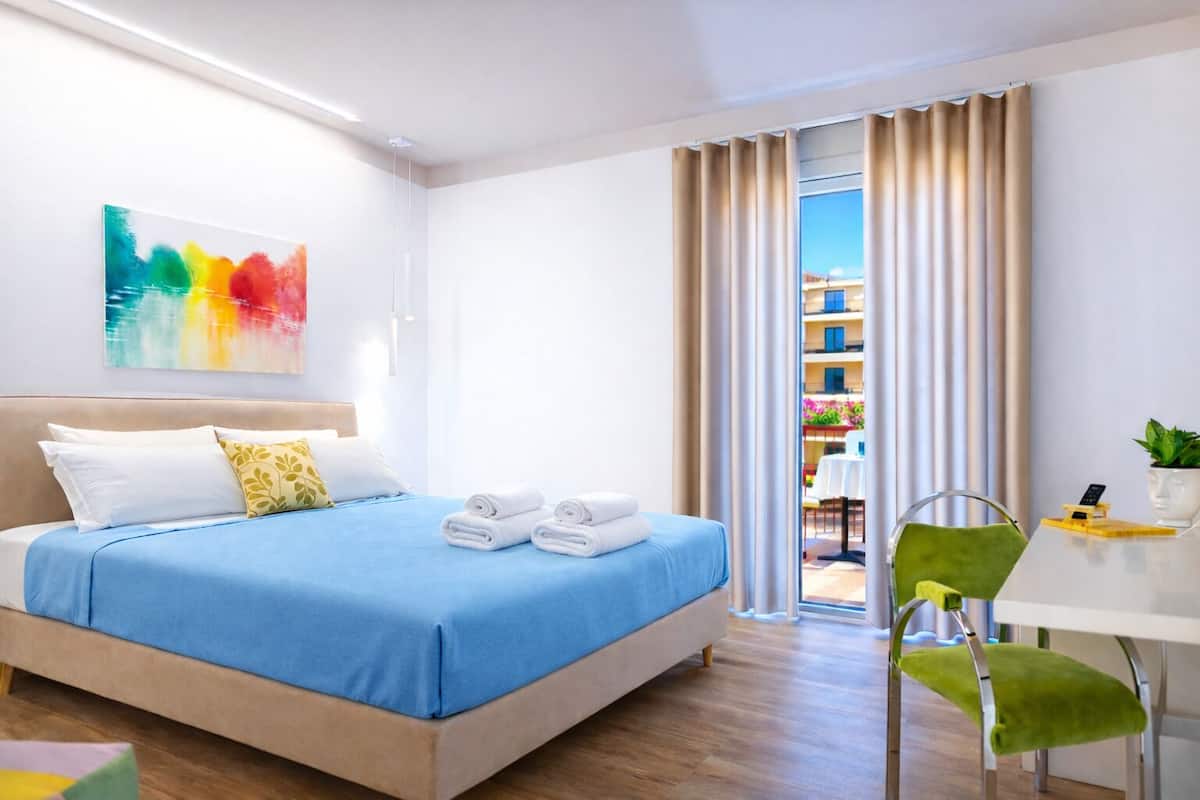 Una habitación de hotel moderna con cama, escritorio, silla y vistas al exterior.