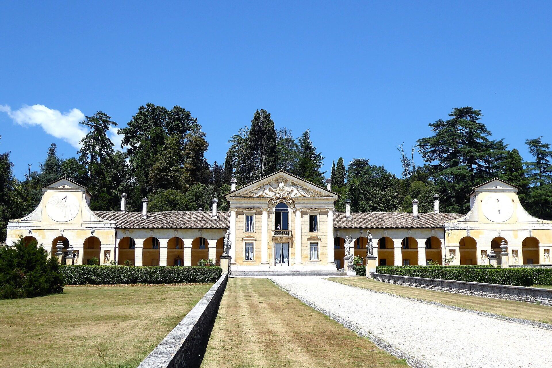A classical building with a central entrance, flanked by symmetrical wings, and a central courtyard with a gravel path.