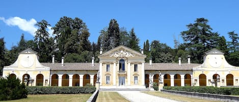A classical building with a central entrance, flanked by symmetrical wings, and a central courtyard with a gravel path.