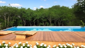 Piscina com deck de madeira e flores brancas em primeiro plano.