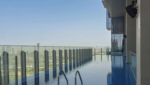A rooftop infinity pool with a glass balustrade, offering a city view. - Balcony with City View 2 Bedroom - JLT Dubai Close to Metro & Marina by Heaven Crest Vacation Homes (Dubai)