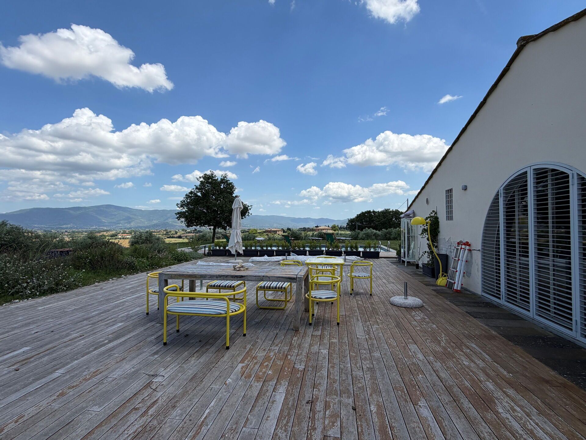 Un patio in legno con mobili da esterno, un tavolo e sedie.