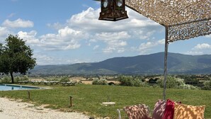 Eine Terrasse mit einer Couch, einem Tisch und einer hängenden Laterne.