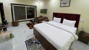 A hotel room with a large bed, a desk with a chair, a coffee maker, and a plant. - The River Park Resort (Jagdalpur)