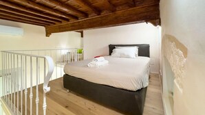 Un dormitorio con cama, techo de madera y balcón con barandilla.
