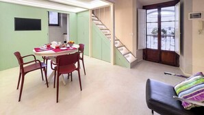 Un comedor con una mesa dispuesta para cuatro personas, una escalera y una vista por una puerta.