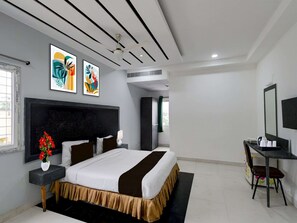 Ein modernes Hotelzimmer mit einem großen Bett, einem Schreibtisch mit Stuhl, einem Fernseher und Kunstwerken an den Wänden.