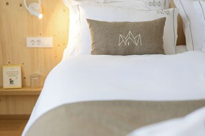 A neatly made bed with a pillow featuring a mountain design, a bedside table with a glass, and a wall socket. - Alpine Escape: 3BR Villa with Private Jacuzzi & Sauna in Bohinj (Bohinj)