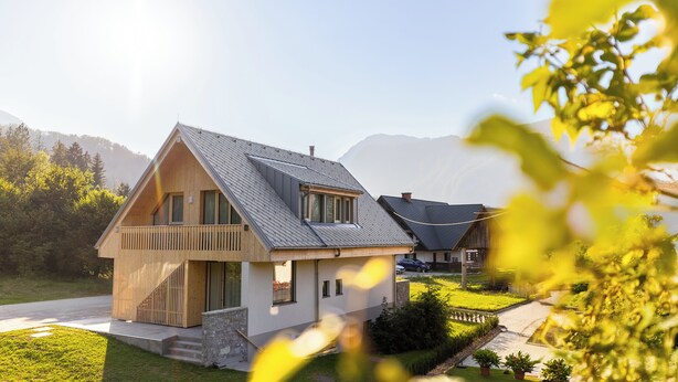 A modern two-story house with a sloped roof, a balcony, and a well-maintained lawn.