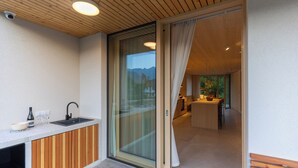 A modern kitchen with a wooden countertop, a sink, and a glass door leading to a dining area.