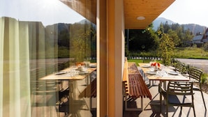 An outdoor dining area with tables set for two, benches, and chairs.