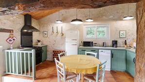 Eine rustikale Küche mit Esstisch, Holzbalkendecke und einem weißen Kühlschrank.