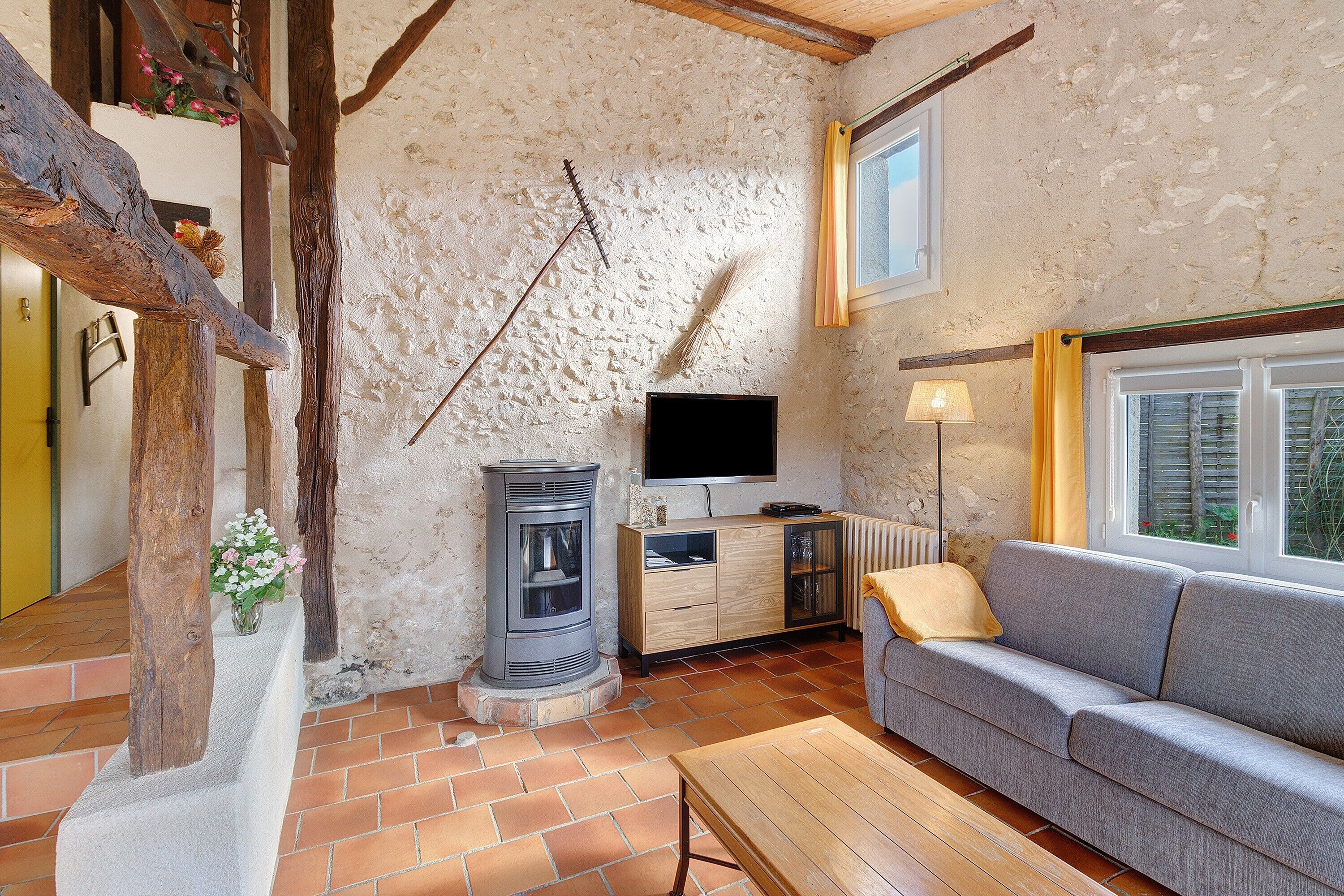 A rustic interior with a stone wall, a fireplace, a sofa, and a television.