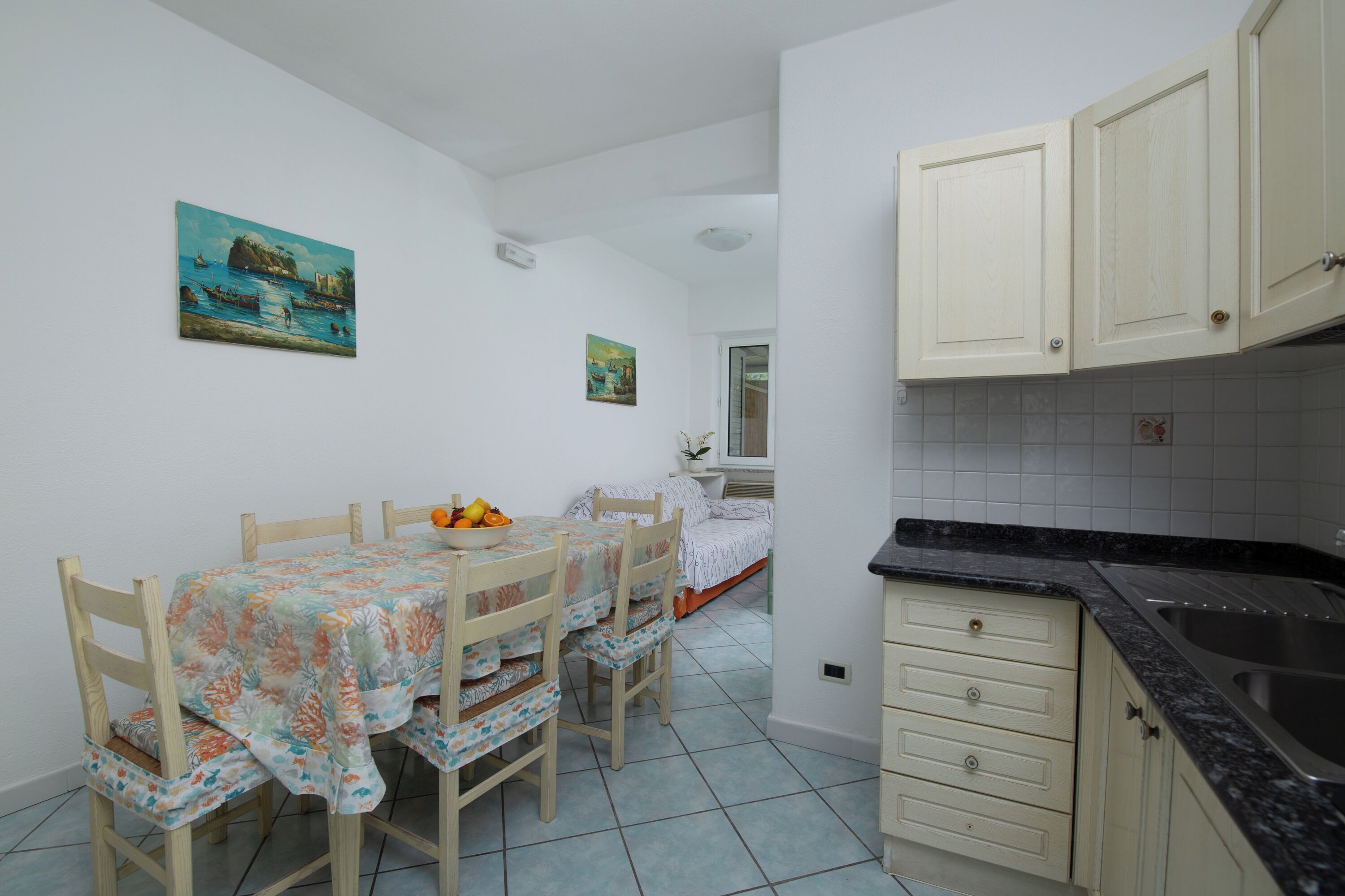 A compact kitchen with a dining area, featuring a tiled backsplash, wooden cabinets, and a small table with chairs.