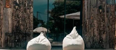 A pool area with two bean bags and a wooden building with a tiled roof.