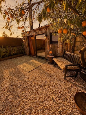 A rustic outdoor seating area with a wooden bench and table, surrounded by a gravel floor and a wooden fence. - Finca Lessya Estate, Cocon du Patio Lodge (Mauguio)