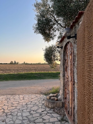 A rustic building with a stone wall, a weathered door, and a paved entrance. - Finca Lessya Estate, Cocon du Patio Lodge (Mauguio)
