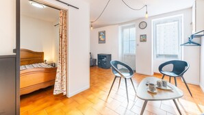 Une pièce comprenant un lit, une table avec deux chaises, une fenêtre et une porte.