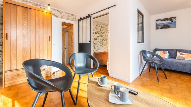 Un salon moderne comprenant un canapé, deux fauteuils, une table basse et un téléviseur.