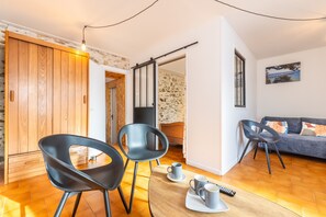 Een moderne woonkamer met een bank, twee fauteuils, een salontafel en een televisie.